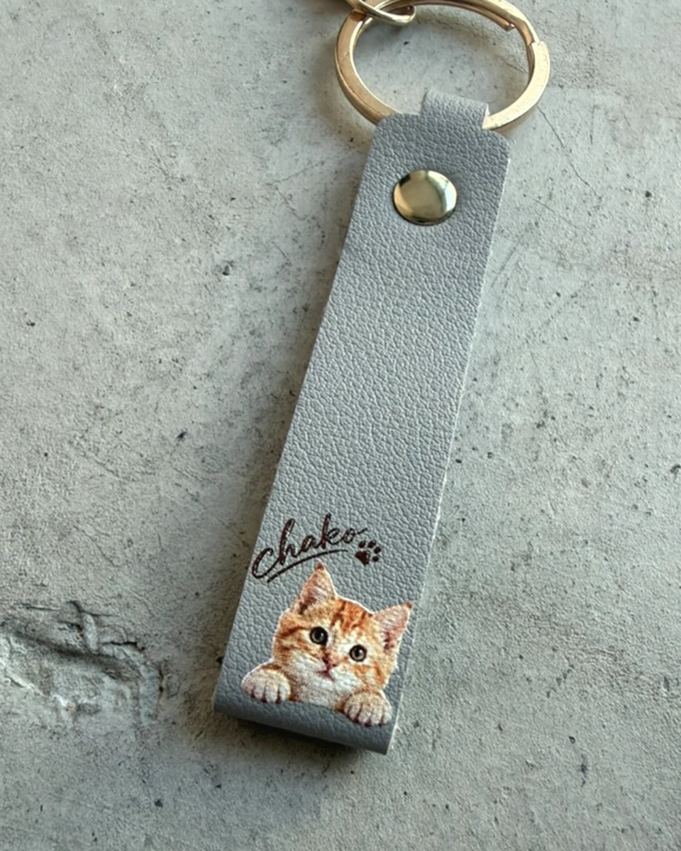 猫の写真と名前をプリントしたグレーのレザーキーホルダー